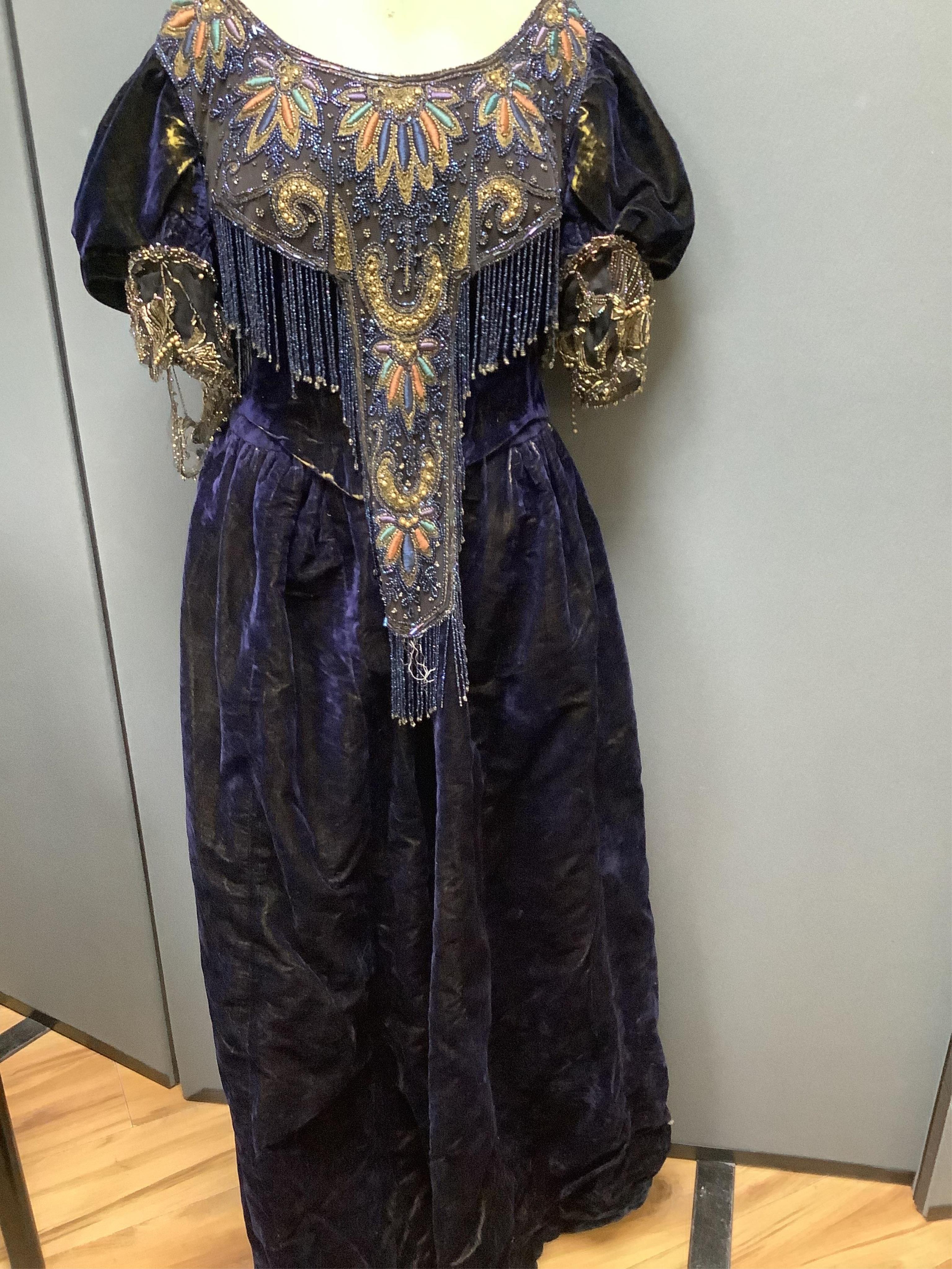 A 19th century ladies silk velvet matching long sleeved jacket/bodice, and skirt, together with another matching short sleeved bead worked bodice and white feather headdress.(4). Cape 106cm long. Condition - Both bodices